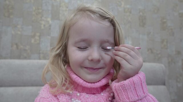 Cute Child Pretending to Apply Makeup and Do Mascara,  Little girl paints eyelashes with mascara for Christmas