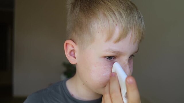 Cute 10 years old boy applying mineral sunscreen stick on his face. Caucasian child protecting freckled skin from sun damage with spf stick at home.
