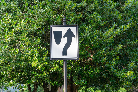 Essential Road Sign: Lane Ends, Merge Left warning sign for safe driving against lush green foliage, advising caution and smooth traffic flow on a clear day.