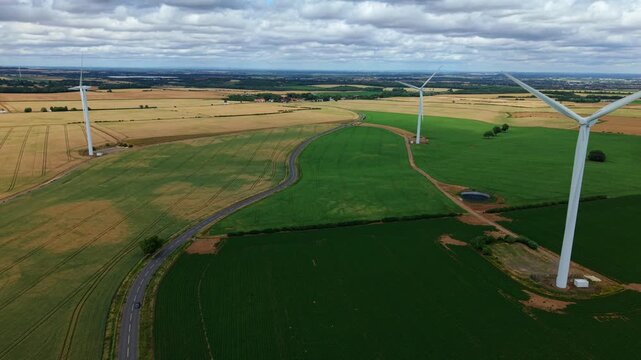 Aerial view of Marr wind farm turbines standing in the colorful patchwork fields of the rural landscape near Doncaster, South Yorkshire, UK.