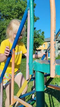 Little girl climbing colorful ladder on playground, Active little girl in yellow t-shirt climbing outdoors