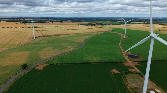 Aerial view of Marr wind farm turbines standing in the colorful patchwork fields of the rural landscape near Doncaster, South Yorkshire, UK.