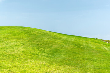 Fototapeta premium Green grass hill under blue sky minimal landscape background