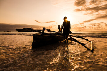 Rybak na tradycyjnym katamaranie wracający z połowu o wschodzie słońca na plaży Zanzibaru Tanzania © kubikactive