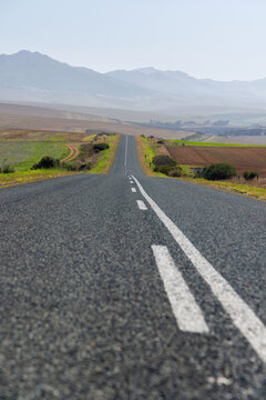 Endless road to horizon through fields and mountains