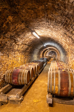 Wine cellar with wooden barrels aging in ancient tunnel