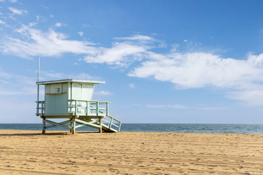 Empty sandy beach with lifeguard tower under blue sky