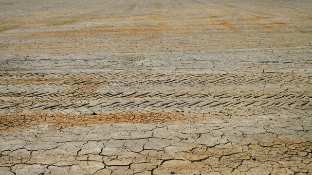 Close-up of cracked dry soil. Parched ground caused by prolonged drought and extreme heat. Climate change, desertification, water scarcity and environmental crisis concept. High quality 4k footage