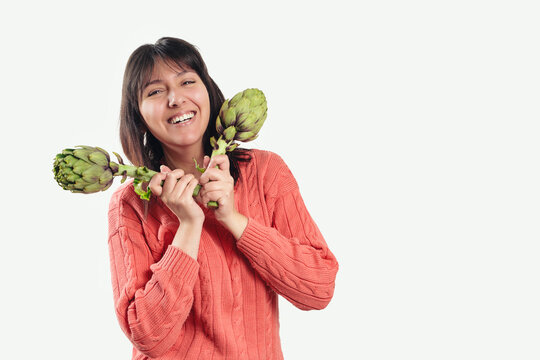 Woman smiles brightly while holding two artichokes