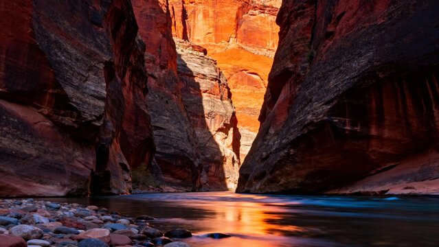 Sunlit canyon with reflective river and colorful rock formations
