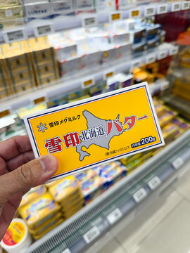 PENANG, MALAYSIA - MAY 29, 2026: Hand holding Snow Brand Hokkaido butter inside supermarket refrigerated dairy section.