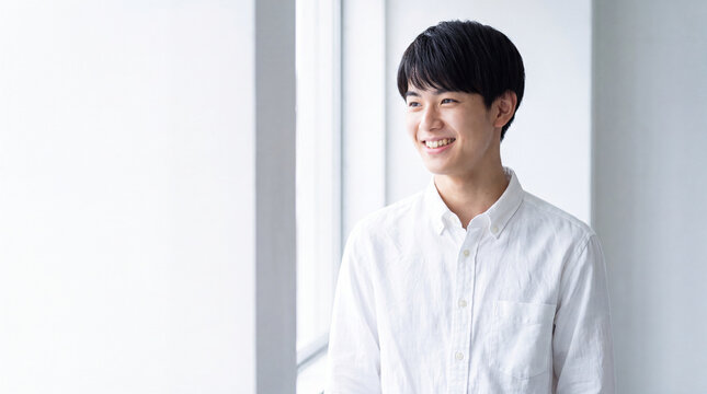 白いシャツを着て横を向いて爽やかに微笑む若い男性 | 白背景