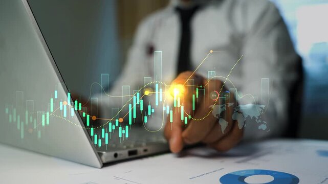 Business person using a laptop and touching a digital holographic chart overlay at a desk, Business data analysis finance planning and modern office work