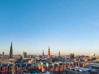 Obraz premium Hamburg, Germany - March 04, 2026: Panoramic aerial view of Hamburg Speicherstadt and historic church towers at sunset