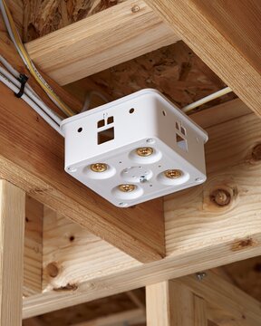 Medium shot of ceilingrated nonmetallic junction box secured to ceiling joists designed for safe fixture mounting and electrical enclosure.