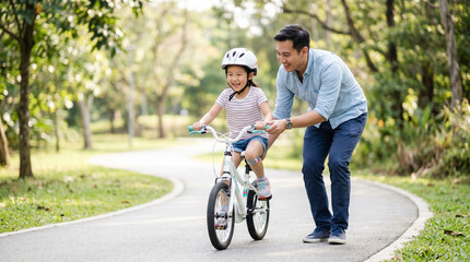 Obraz premium Father helping daughter learn to ride bicycle on sunny park path