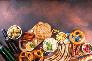 Fototapeta premium Oktoberfest picnic and barbecue food, bavarian party menu, bavarian sausages, pretzels, potato, sauerkraut, beer bottles, with picnic basket, checkered napkin tablecloth, Oktoberfest festive ribbon