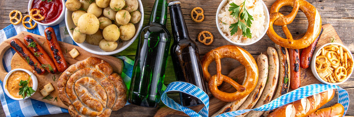 Fototapeta premium Oktoberfest picnic and barbecue food, bavarian party menu, bavarian sausages, pretzels, potato, sauerkraut, beer bottles, with picnic basket, checkered napkin tablecloth, Oktoberfest festive ribbon