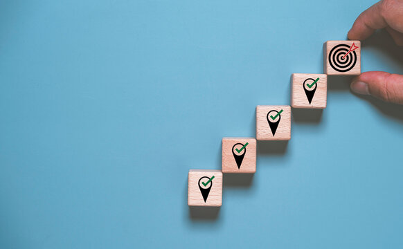 Wooden blocks forming an upward path to a target icon, representing goal achievement, business success, strategic planning, milestone progress, productivity and continuous growth.