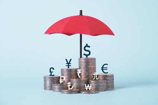 Red umbrella protecting stacked coins and global currency symbols, representing financial protection, wealth management, investment security, asset protection, risk management and financial stability.