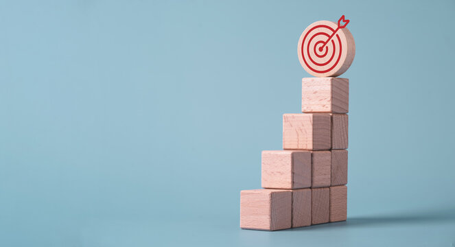 Wooden blocks stacked upward with a target icon on top symbolizing for target growth, business success, goal achievement, strategic planning, performance improvement and sustainable growth.