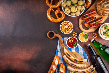 Fototapeta premium Oktoberfest picnic and barbecue food, bavarian party menu, bavarian sausages, pretzels, potato, sauerkraut, beer bottles, with picnic basket, checkered napkin tablecloth, Oktoberfest festive ribbon