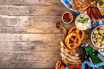 Fototapeta premium Oktoberfest picnic and barbecue food, bavarian party menu, bavarian sausages, pretzels, potato, sauerkraut, beer bottles, with picnic basket, checkered napkin tablecloth, Oktoberfest festive ribbon