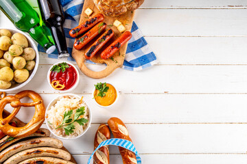 Fototapeta premium Oktoberfest picnic and barbecue food, bavarian party menu, bavarian sausages, pretzels, potato, sauerkraut, beer bottles, with picnic basket, checkered napkin tablecloth, Oktoberfest festive ribbon