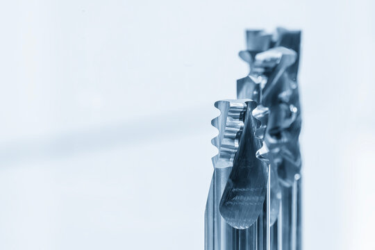 Macro photograph of a group of solid carbide end mill special cutting tools for CNC milling machine, isolated in a high-tech light blue scene.