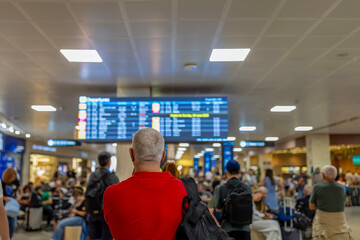 Obraz premium Traveler looking at airport departure arrival board