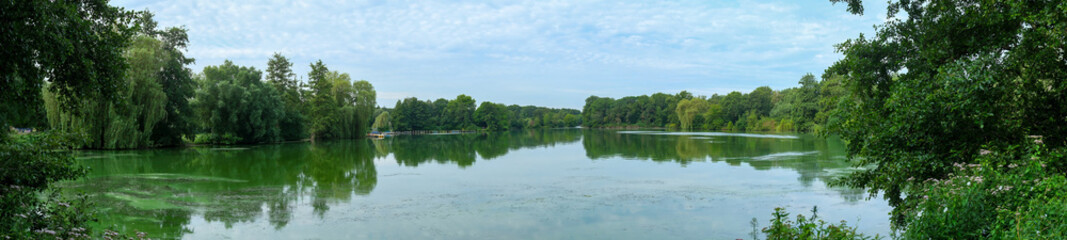 Obraz premium Panoramic Photo, Lake Proepsting, Panoramic wide shot of serene lake reflecting green trees. Borken, NRW, Germany,