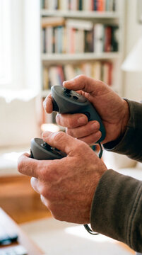 Close up of hands gripping virtual reality controllers in a bright living room at home