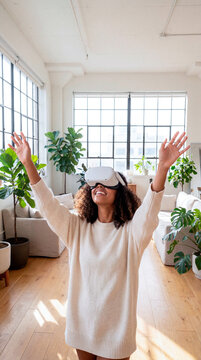 Excited woman raising her arms while enjoying virtual reality with a headset at home