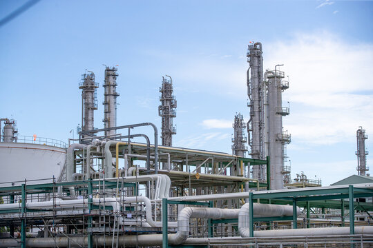 Industrial landscape featuring tall chemical processing towers and pipelines against a clear blue sky