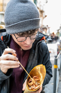 Naples, italy. December 27, 2024. Young man enjoying a delicious cuoppo of mixed fried seafood street food in spaccanapoli, naples, italy