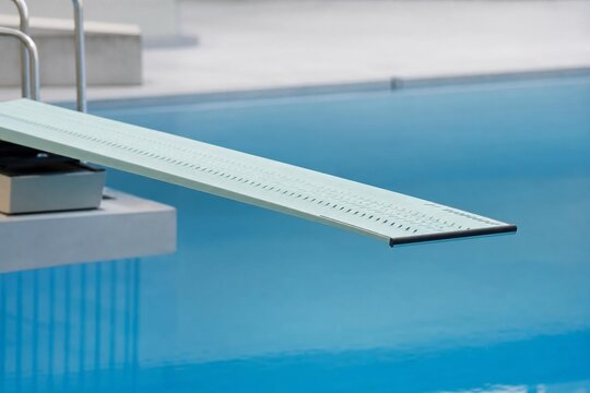 A professional diving springboard curving over calm blue pool water.