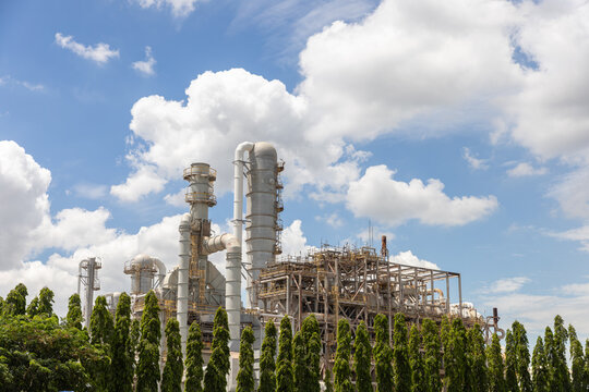 Industrial plant with towers against a blue sky surrounded by greenery showcasing engineering and construction work