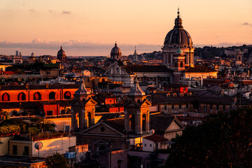 Historic European city skyline with domes and terracotta rooftops bathed in golden sunset light over classical Baroque architecture © PIC by Femke