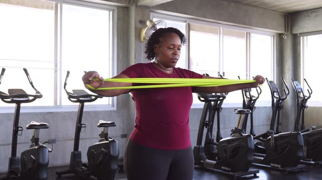 African American woman training with resistance bands in a gym, improving strength, mobility and fitness while promoting healthy aging.