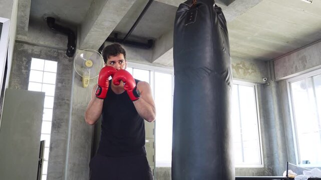 Muscular boxer in a defensive stance training with a heavy bag in a loft gym, building strength, discipline and fitness through boxing workouts.