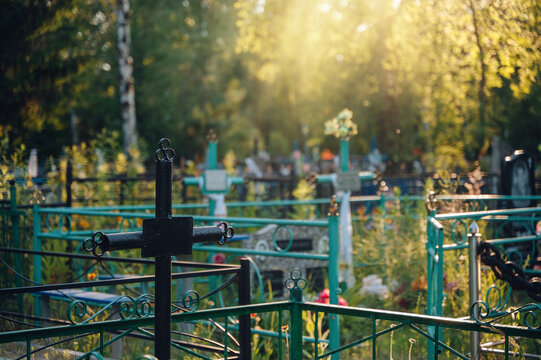 Silhouette of a black metal cross on a grave during a beautiful dramatic sunset, spiritual memory concept