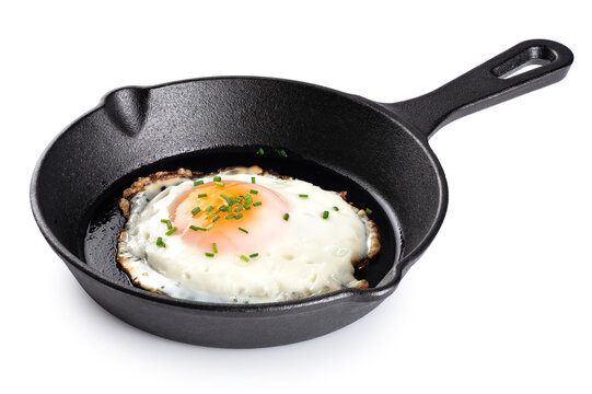 Fried egg with green onions on a cast iron mini frying pan isolated on a white background. With clipping path.