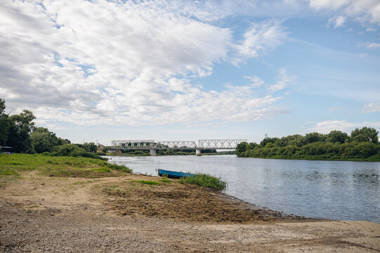 peaceful riverbank scene with boat and bridge in rural landscape photography periodical editorial resource for travel imagery and nature scenes design and visual story.