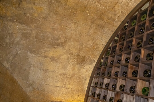 A wine cellar in the ancient basement of a medieval house.  There are bottles of wine on the shelves in the cellar. A vaulted stone basement in an old house.