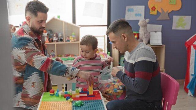Man and boy stacking colorful plastic blocks with hands at a small table in a playroom building; playful bonding.