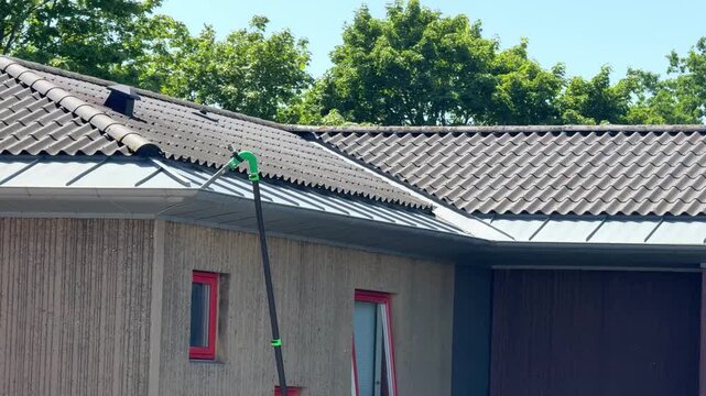 Roof gutter cleaning with vacuum maintenance on residential house