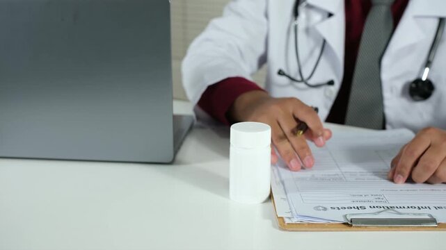 Doctor holding bottle of pills and writing prescription  in clinic. Prescribing medications for patients. Healthcare, medical and pharmacy industry concept
