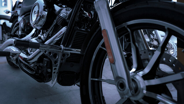 Selective focus on motorcycle frame. Closeup motorcycle exhaust pipe, engine guard, and foot rest. Motorcycle industry. Shiny chrome motorbike engine. Vintage motorbike. Blur aluminum alloy wheel.
