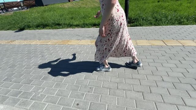 A Caucasian woman with mild cerebral palsy walks down the street. Close-up of legs.