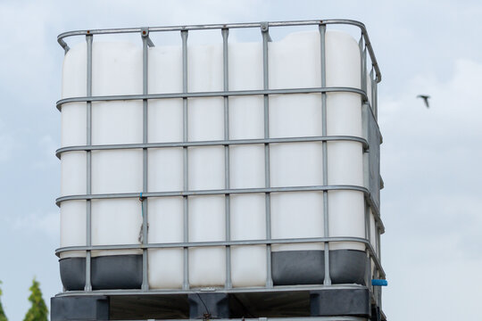 white ibc container in outdoor stock yard of factory, white plastic chemical tanks.